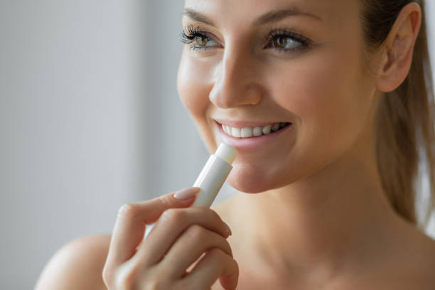 wanita muda menggunakan pelembap bibir lip balm