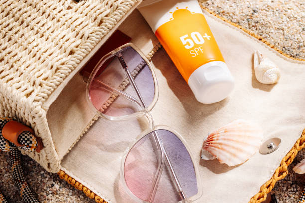 sunscreen 50+ spf dan kacamata fashion di dalam tas rotan pantai