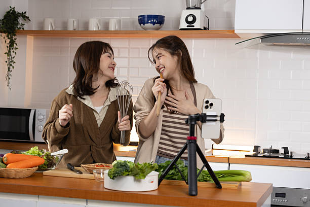 dua anak muda sedang membuat konten masak di dapur menggunakan tripod HP