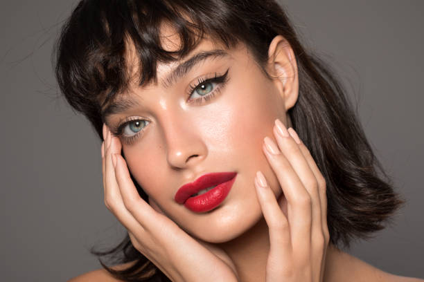 seorang wanita dengan makeup elegan: winged eyeliner dan lipstick merah
