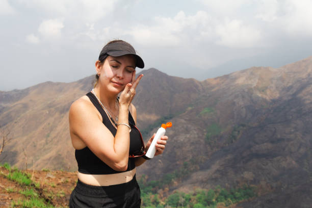 seorang wanita sedang reapply sunscreen saat hiking ke gunung