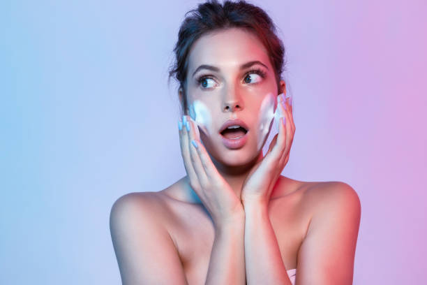 seorang wanita muda menggunakan sedang mencuci muka menggunakan busa sabun