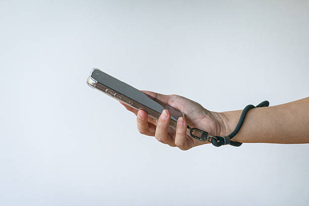 seseorang menggenggam handphone dengan tali gantungan HP