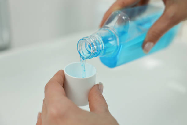 seseorang sedang menuangkan obat kumur ke dalam tutup botolnya