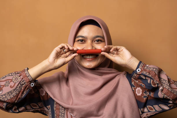 seorang wanita berhijab dengan undertone sawo matang memegang lip tint