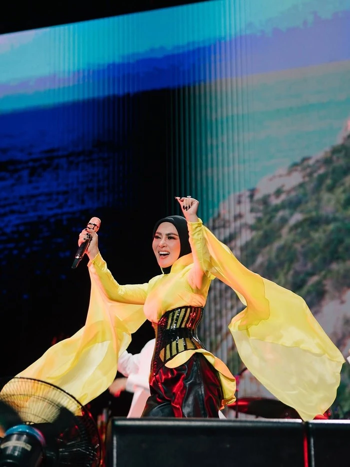 Gaya Bold Syahrini di Pestapora: Corset Hitam, Cape Kuning, dan Boots Statement