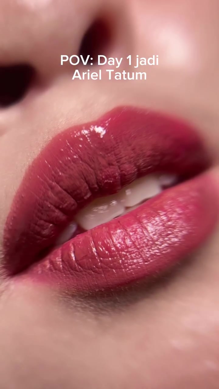 Close-up bibir dengan lapisan lip stain glossy merah muda yang sudah merata