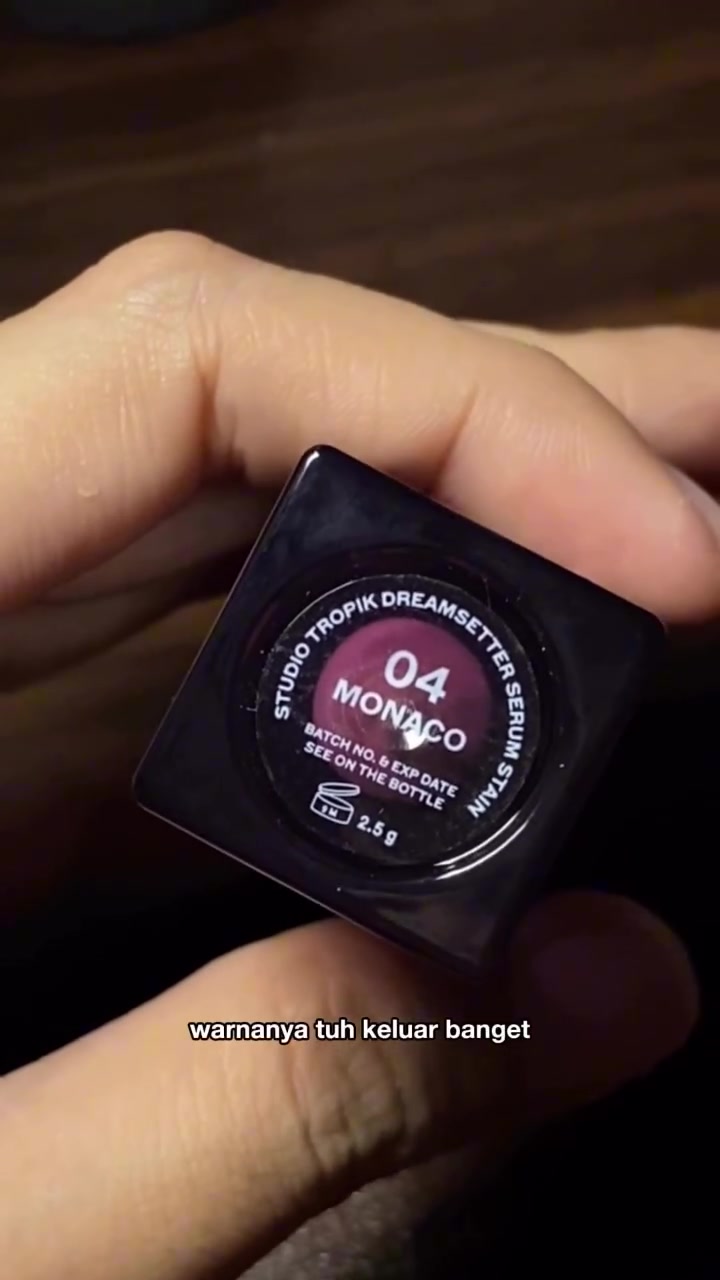 Tangan memegang bagian bawah botol Studio Tropik Dreamsetter Serum Stain sehingga label shade 04 Monaco dan keterangan isi 2,5 g terlihat