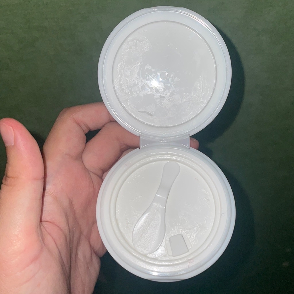 Jar cleansing balm terbuka dilihat dari atas dengan spatula kecil tersimpan di tutup bagian dalam