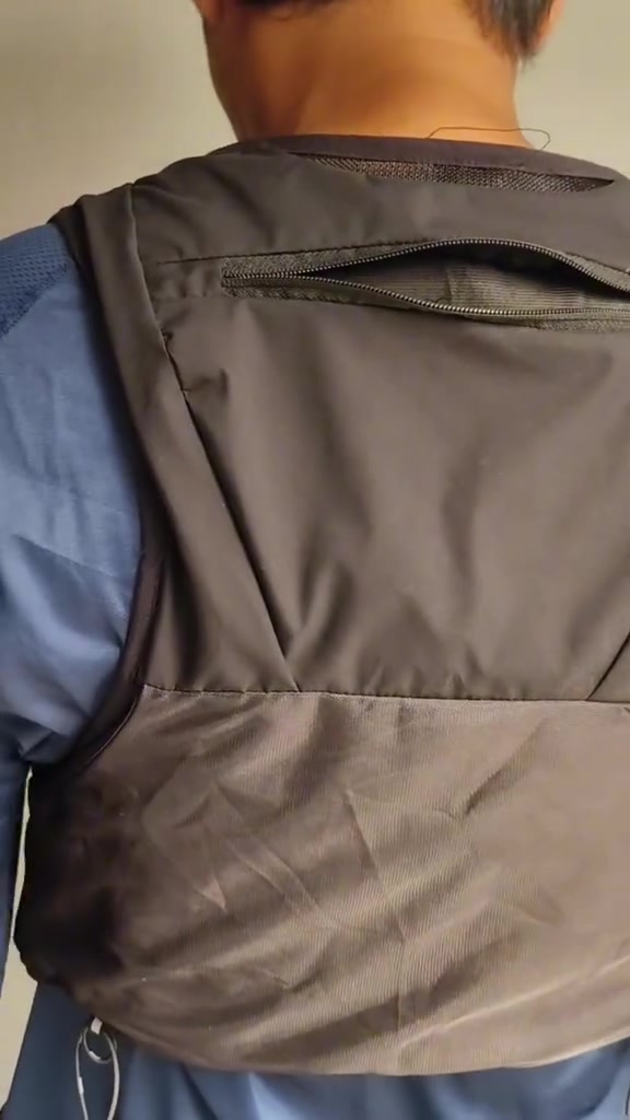 Tampak belakang hydration vest abu-abu dengan kompartemen beritsleting di punggung
