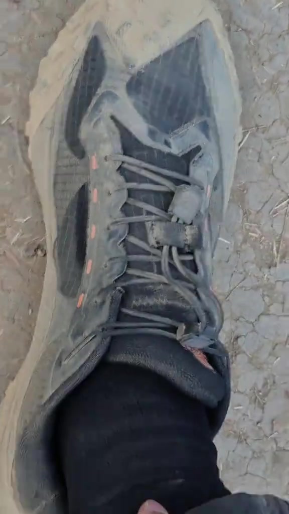Sepatu Ardiles ATF Jasper hitam berdebu dipakai berdiri di tanah kering, dilihat dari atas