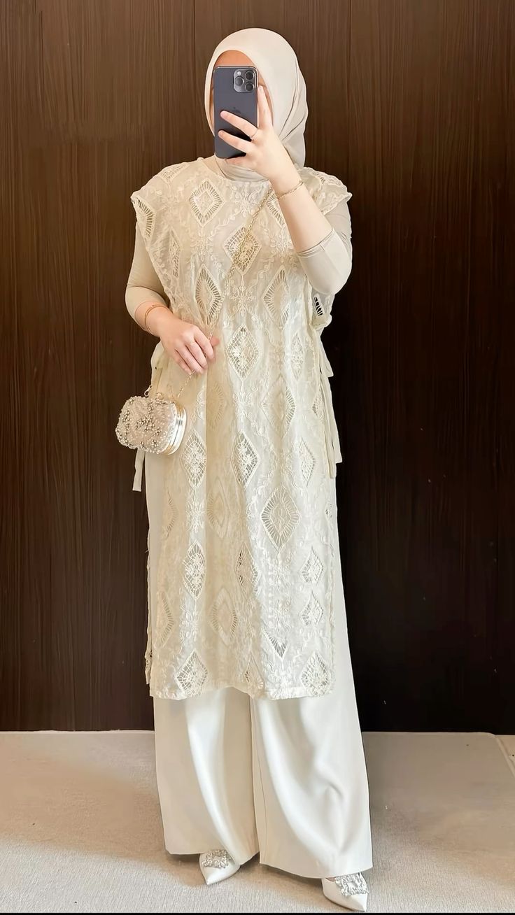 Vest outer brokat motif belah ketupat warna cream di atas inner beige dan kulot putih, dengan tas pearl