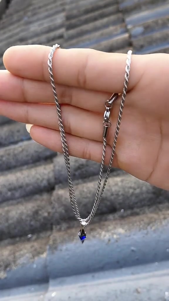 Rantai kalung silver dijuntai di tangan dengan pengaitnya terlihat jelas