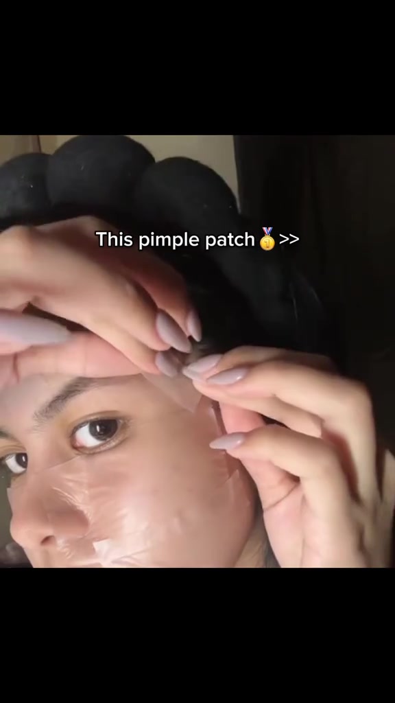 Close-up jari menekan acne patch hydrocolloid bening yang ditempel di area pelipis