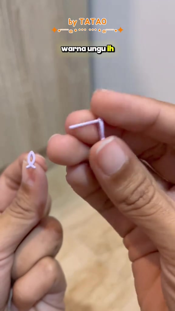 Jari memegang anting tusuk keramik warna lavender bentuk pita beserta tiangnya