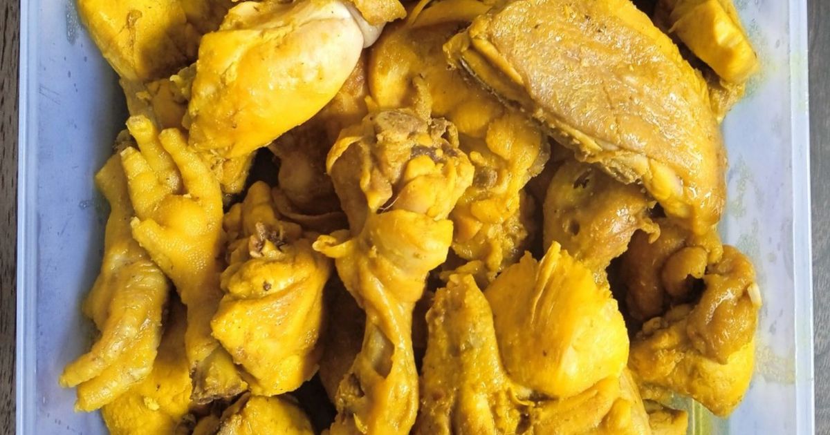 Potongan ayam ungkep bumbu kuning tersusun rapat dalam wadah plastik penyimpan
