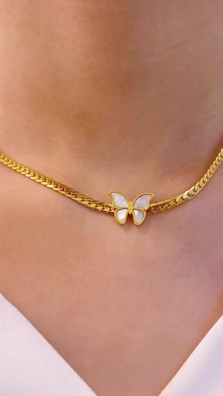 Kalung rantai emas dengan liontin kupu-kupu berwarna putih dipakai pas di tulang selangka