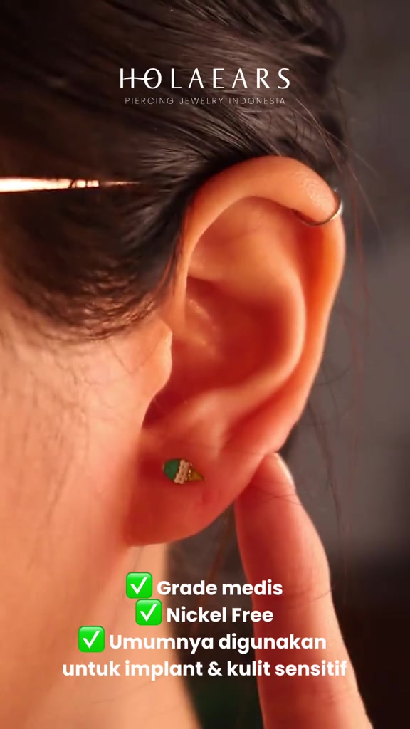 Close-up telinga dengan anting tusuk mungil dan hoop tipis di bagian helix