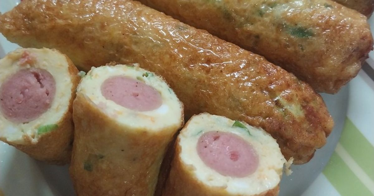 Potongan sostel goreng berkulit keemasan mengilap dengan penampang sosis di tengah, disusun bersama tusukan utuh di piring