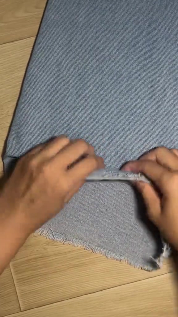 Tangan melipat hem celana jeans ke arah dalam sebagai trik agar hem tidak menyentuh genangan air
