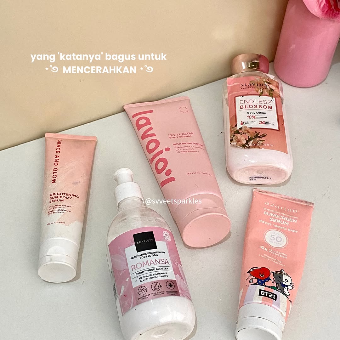 Lima produk body care pencerah kemasan pink terbaring di permukaan krem, dari tube serum sampai botol lotion pump