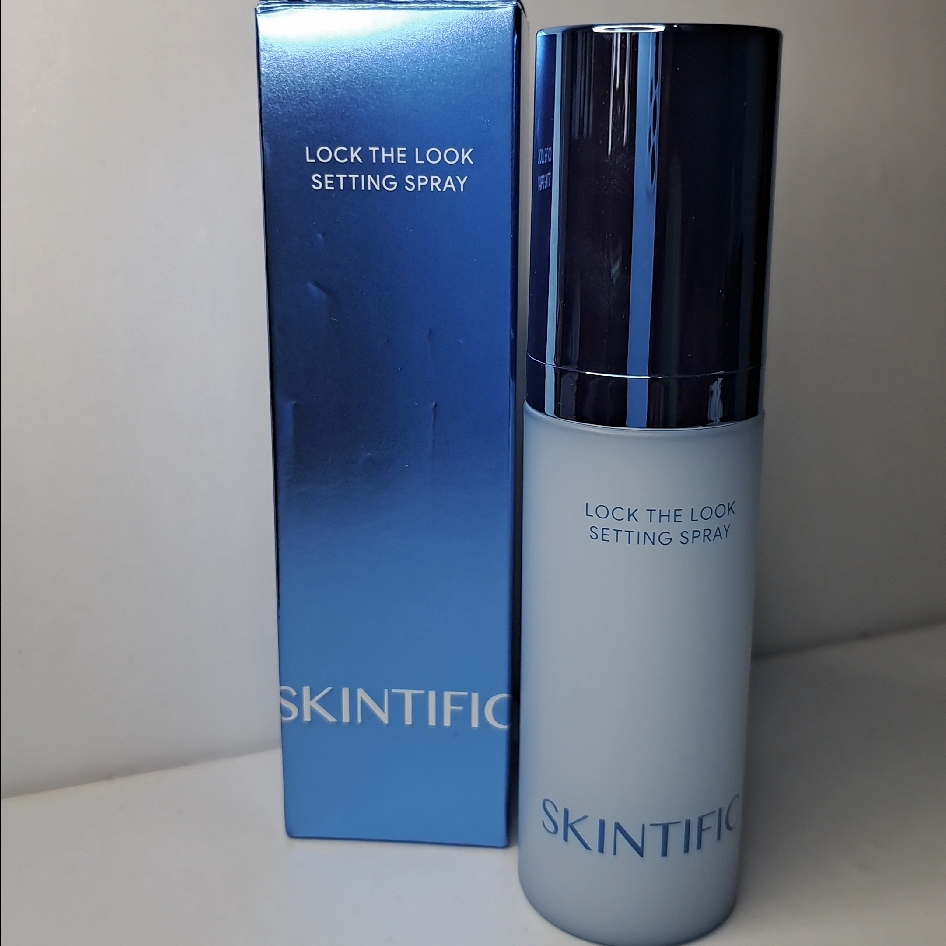 Botol Skintific Lock The Look setting spray berwarna biru muda berdiri di samping kotak kemasannya