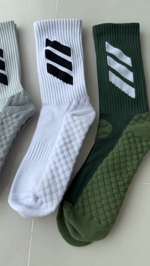 Tiga kaos kaki lari model crew warna putih dan hijau dibentangkan berdampingan memperlihatkan rajutan berbantalan di bagian telapak