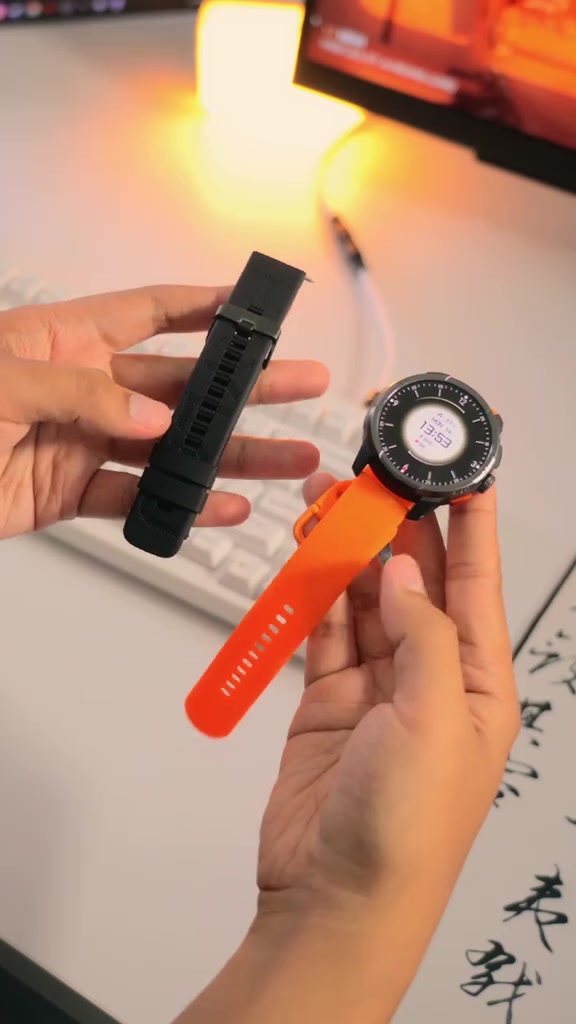 Haylou Solar Ultra berstrap oranye dipegang di tangan, disertai strap hitam cadangan