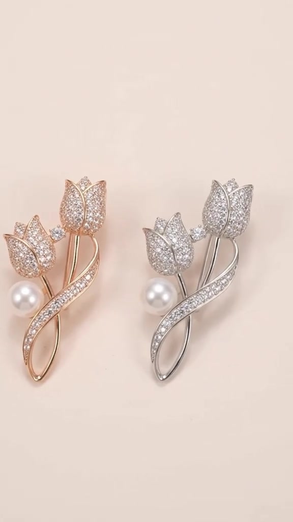 Dua bros bunga tulip bertabur zirconia dengan aksen mutiara warna gold dan silver di atas latar krem