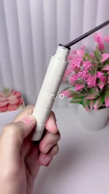 Tangan menarik wand baja tipis keluar dari tube maskara barenbliss warna krem