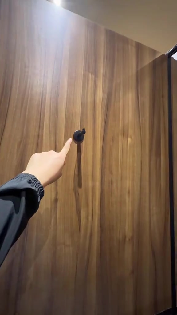 Tangan menunjuk deretan gantungan pada dinding kayu ruang ganti studio hot mat pilates