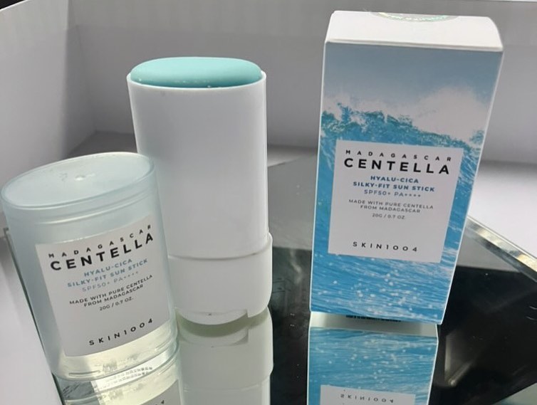 Sunscreen stick SKIN1004 Madagascar Centella terbuka memperlihatkan permukaan balm mint, di samping kotaknya