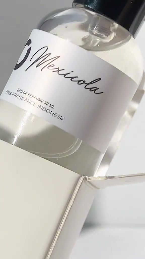 Close-up botol ONIX Mexicola eau de perfume 30 ml berlabel putih di atas kotak pembukaannya dengan cahaya lembut