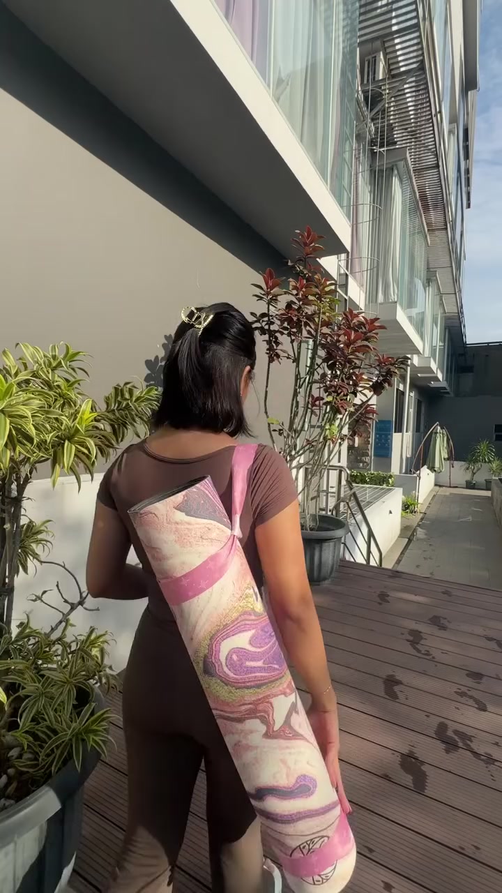 Punggung perempuan membawa matras tergulung dengan tali selempang menuju kelas