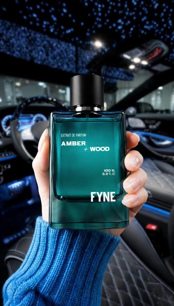 Tangan bersweater biru memegang botol Fyne Amber Wood di dalam mobil dengan plafon berbintang