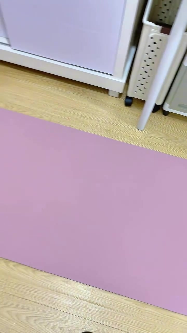 Matras yoga warna lilac terbentang di lantai kayu ruangan rumah