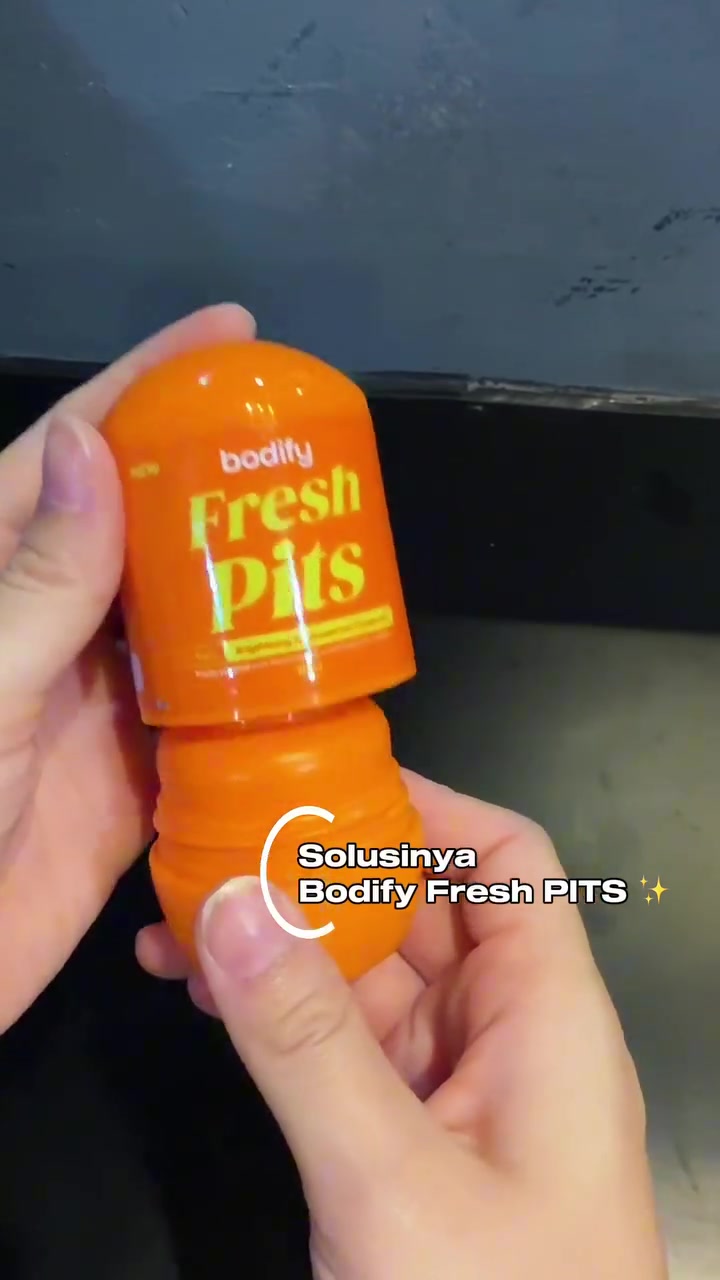 Dua tangan membuka stik antiperspirant Bodify Fresh Pits berwarna oranye