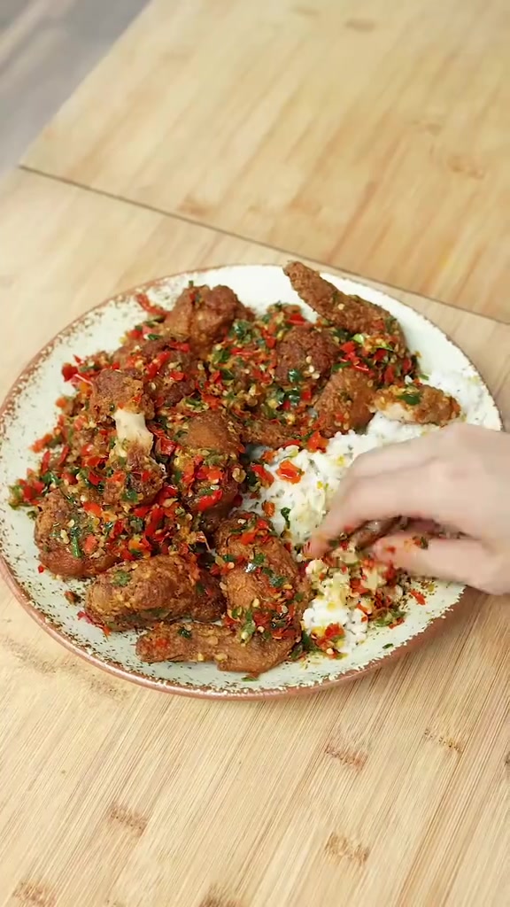 Piring berisi ayam chili padi dan nasi putih di atas meja bambu