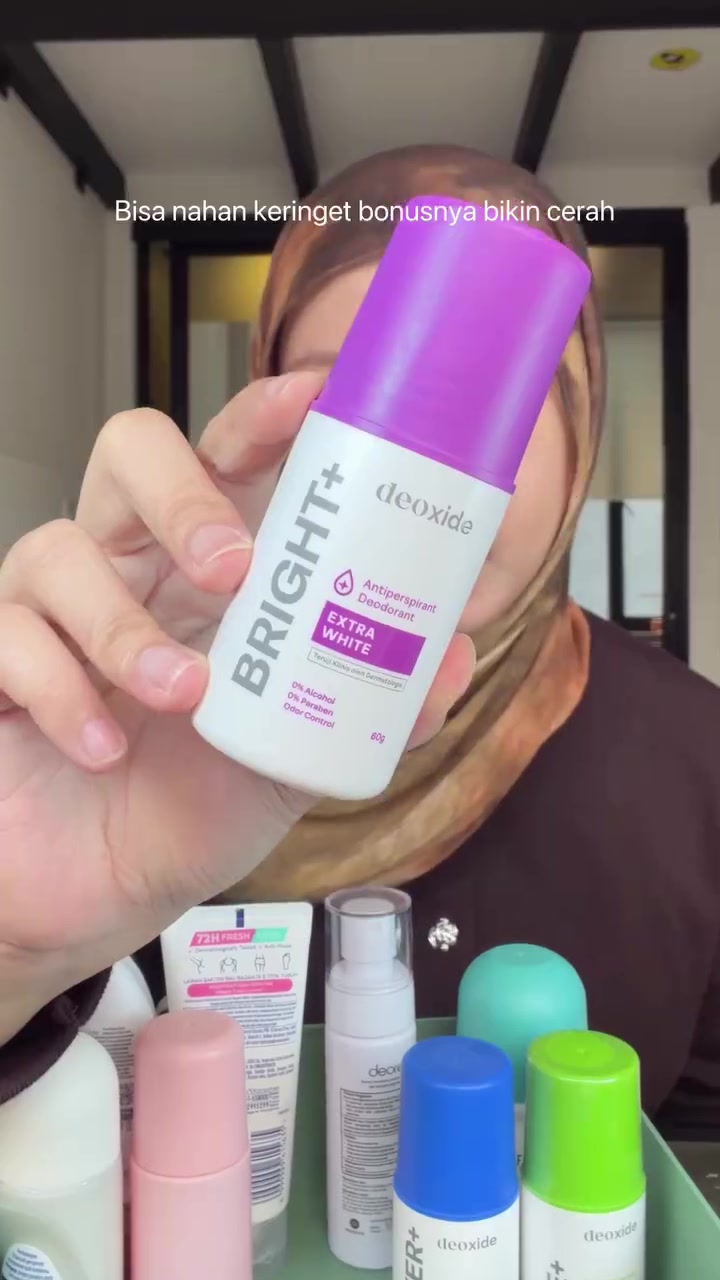 Tangan memegang roll-on Deoxide Bright+ Extra White di depan deretan deodorant varian lain