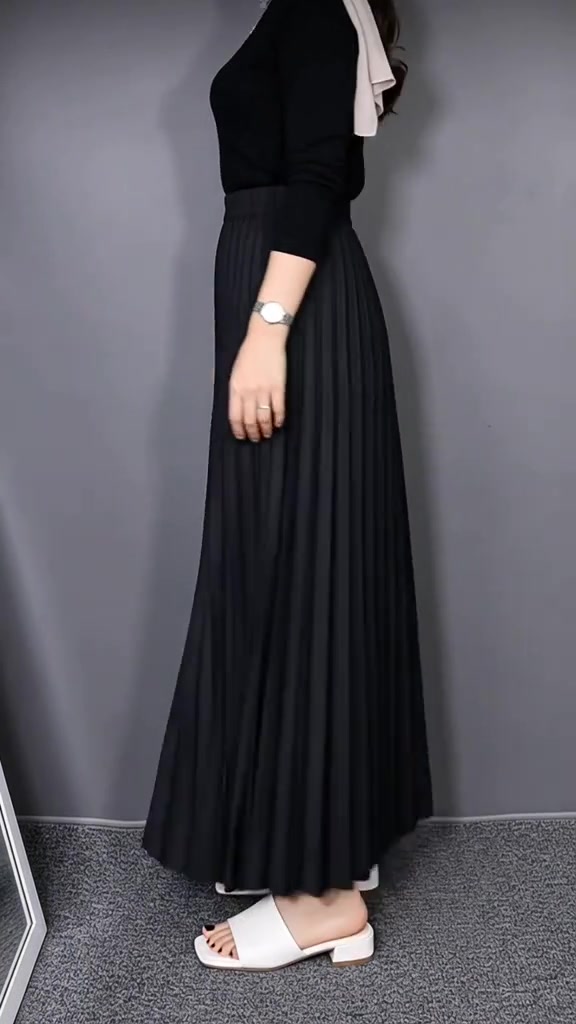 Rok plisket maxi hitam dengan atasan knit hitam tampak samping, dipadu sandal mules putih bertumit rendah