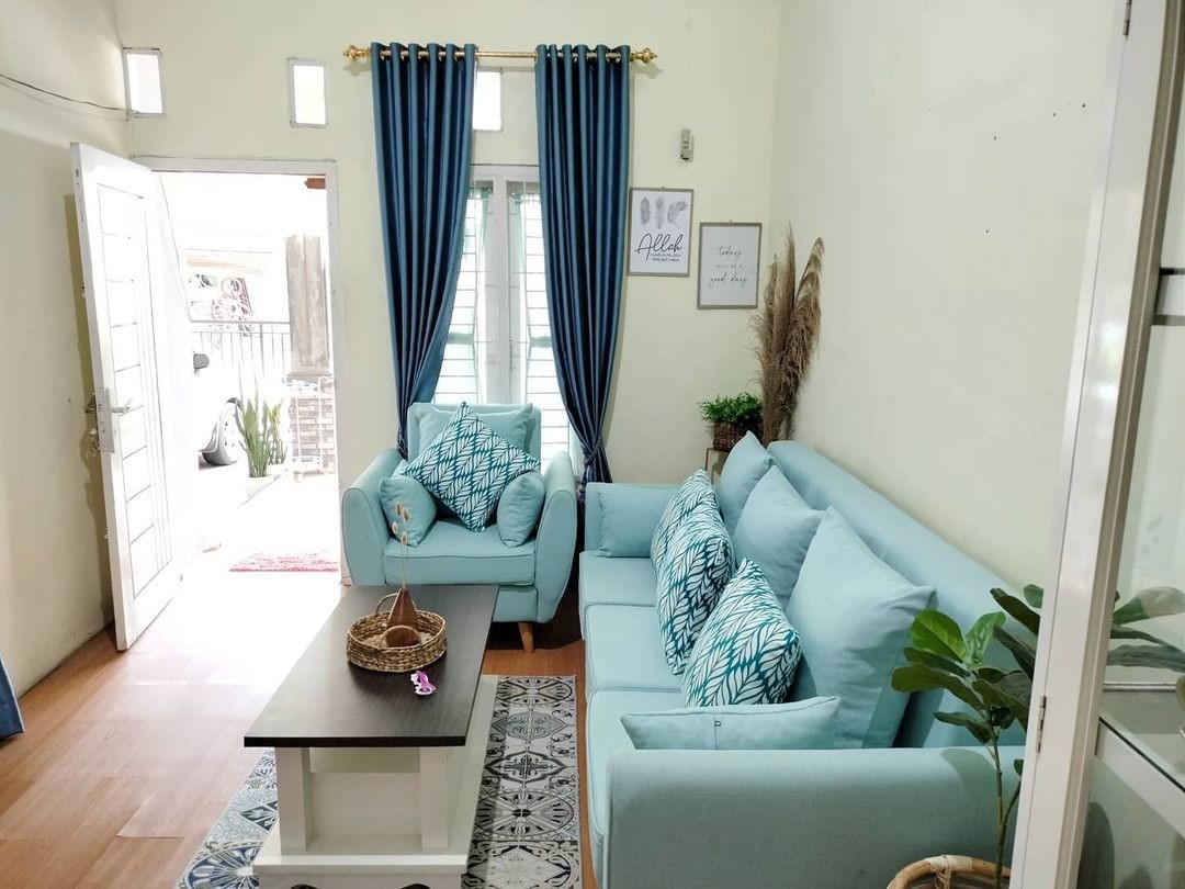 Ruang tamu terang dengan sofa biru muda, bantal motif, gorden navy, dan karpet runner bermotif di lantai kayu
