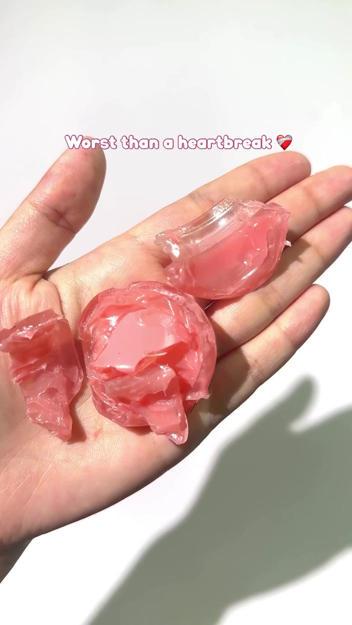 Pecahan gel lip balm warna pink yang meleleh di telapak tangan terbuka