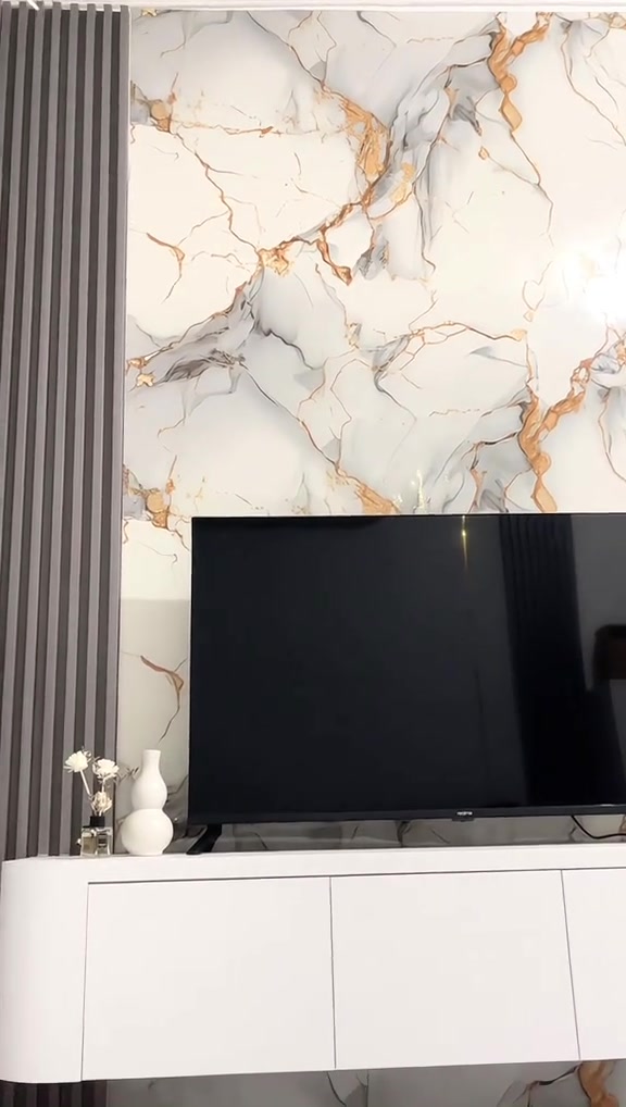 Dinding TV motif marmer dengan panel kayu, bufet putih melayang, dan pencahayaan hangat