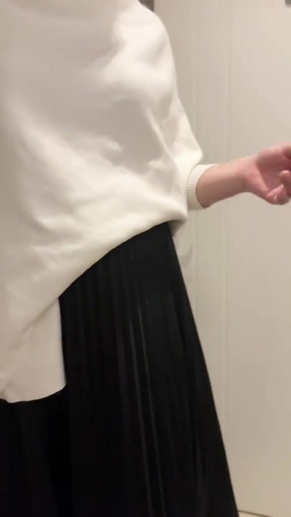 Atasan knit putih asimetris dipadu rok plisket hitam, tampak dari leher ke bawah tanpa wajah