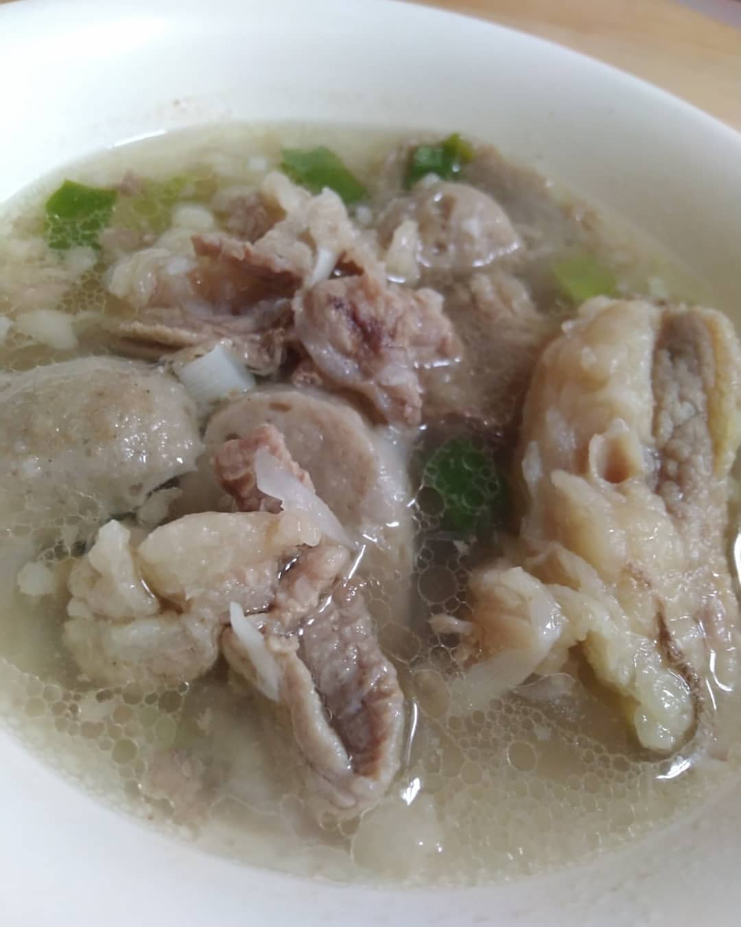 Close-up mangkuk sop tetelan sapi dengan potongan tetelan empuk, bakso, dan irisan daun bawang dalam kuah bening