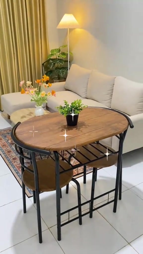 Meja makan oval kayu dengan dua kursi rangka hitam di sudut ruang tamu berdampingan dengan sofa dan lampu lantai