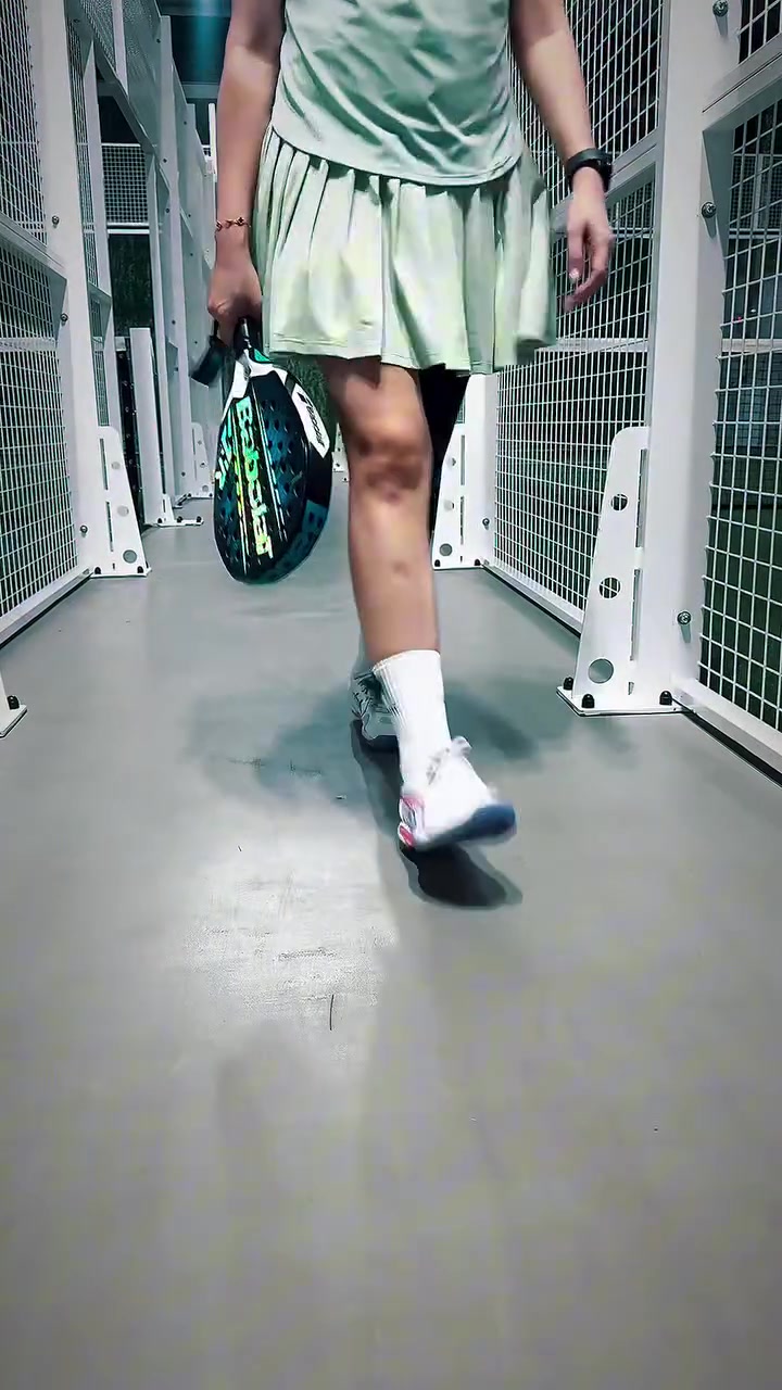 Sepatu court putih dan kaos kaki putih saat berjalan di koridor lapangan padel sambil membawa raket
