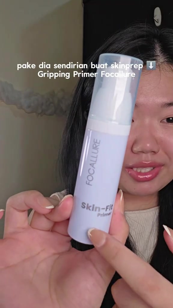 Botol Focallure Skin-Fit Primer warna biru muda dipegang dekat kamera sehingga labelnya terbaca