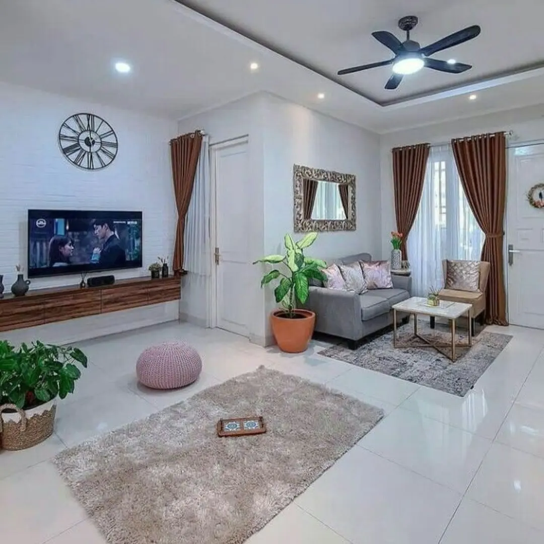 Ruang keluarga dengan meja TV kayu menggantung di dinding, karpet bulu abu-abu, dan pouf rajut merah muda