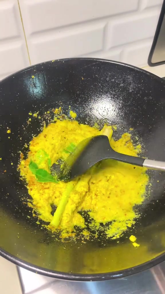 Bumbu halus kuning soto sedang ditumis di wajan bersama serai dan daun jeruk